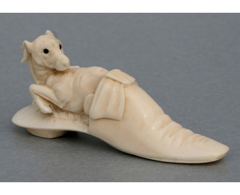 A 19th century ivory walking stick handle in the form of a recumbent whippet, with glass inset eyes, curled up inside a ladie