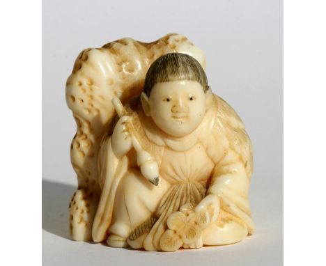 A 19th century Japanese carved ivory netsuke in the form of a boy holding a calligraphy brush, 3.5cms (1.25ins) high.
