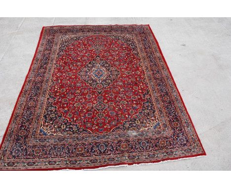 A Persian carpet with central floral medallion on a red ground within a multi floral border, 390 by 298cms (153.5 by 117ins).