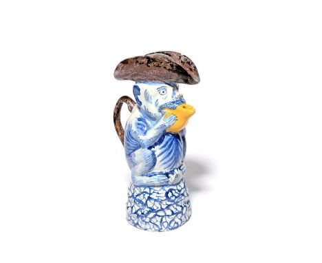 A Delft comical monkey jug and cover, mid 18th century, modelled as a monkey holding a fruit up to its mouth and forming the 