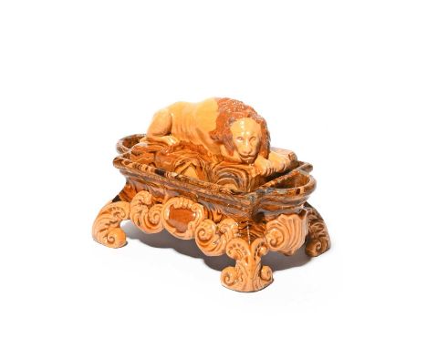 A slipware double inkwell, 19th century, the cover modelled with a recumbent lion, the rectangular base modelled from agatewa