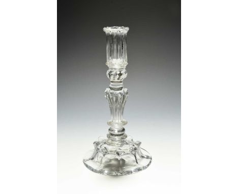 A moulded glass candlestick, c.1720, the tall sconce moulded with vertical flutes, above a beaded knop, raised on a pedestal 