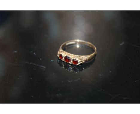 A 9CT GOLD THREE STONE GARNET DRESS RING