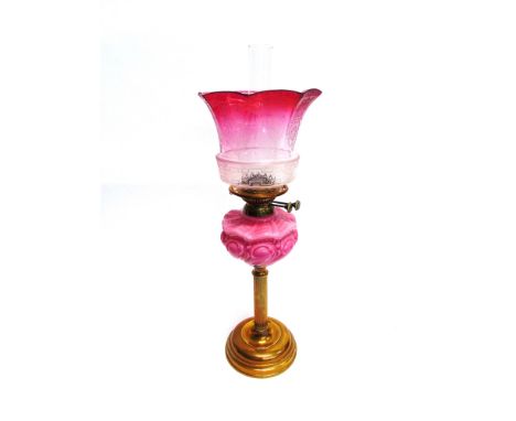 A LATE VICTORIAN / EDWARDIAN OIL LAMP  the cranberry glass shade with etched decoration, opaque pink glass reservoir on brass