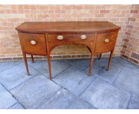AN EARLY 19TH CENTURY MAHOGANY BOW FRONT SIDEBOARD  with central drawer flanked by a pair of deep side drawers and raised on 