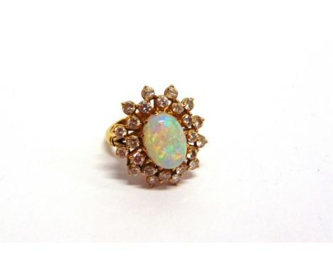 AN OPAL AND DIAMOND CLUSTER RING stamped '18KT', the oval cabochon enclosed by twenty four brilliant cuts, totalling approxim