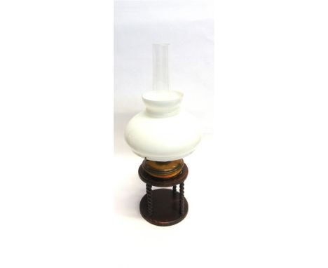AN OIL LAMP WITH OPAQUE GLASS SHADE  and brass reservoir, in an oak stand, 63cm high overall