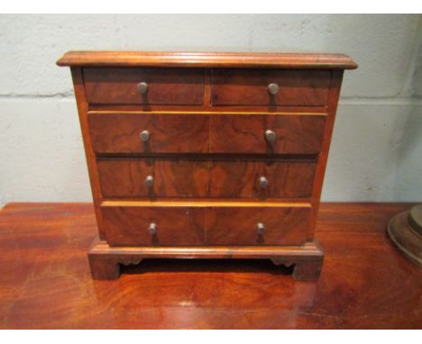 A walnut miniature chest of four long drawers on bracket feet. 27cm tall x 28cm wide x 20cm deep 