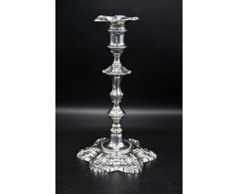 Silver hallmarked George II candlestick. A cast candlestick with gadrooned capital, shell shoulders to a knopped stem, raised