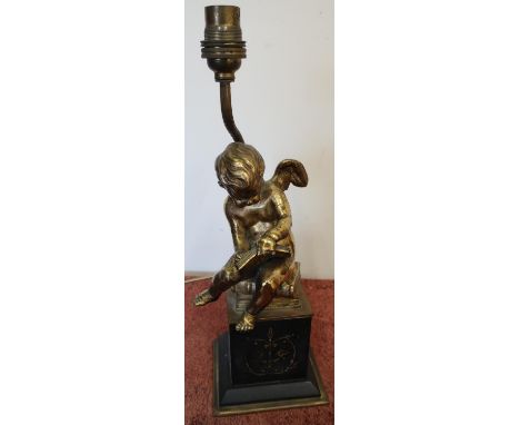 Table lamp in the form of a gilt metal cherub scribing a book, on raised black slate and gilt base (overall height 37cm) 