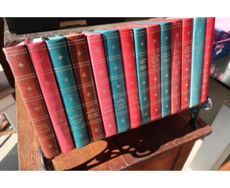 Miniature cast metal garden bench with wooden slats used as a book rack, with a selection of leather bound books (width 39cm)
