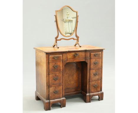 A GEORGIAN STYLE WALNUT KNEEHOLE DRESSING TABLE, the crossbanded and feather banded rectangular top above an arrangement of n