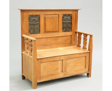 AN ARTS AND CRAFTS OAK SETTLE, the back with two repousse copper panels above a hinged box seat, flanked by arms with splats 