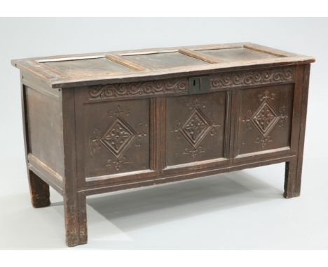 A LATE 17TH CENTURY OAK COFFER, with panel lid, the three panel front carved with lozenges below a scrolling frieze. 66cm hig