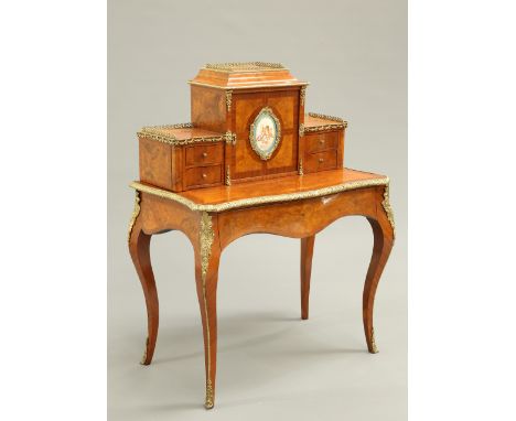 A FINE LOUIS XV STYLE GILT-METAL AND PORCELAIN MOUNTED WALNUT DESK, the superstructure with a cupboard door centred by a Sevr