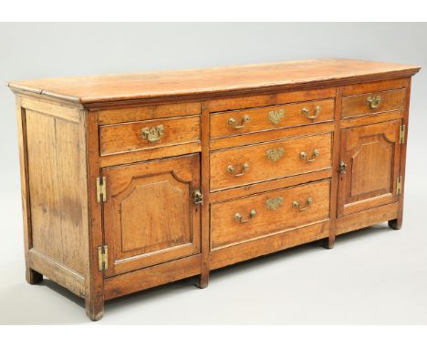 A GEORGE III OAK DRESSER BASE, fitted with an arrangement of five drawers and a pair of fielded panel doors. 78.5cm high, 175