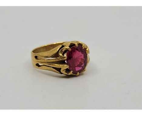 A precious yellow metal and synthetic ruby set ring, set large mixed oval cut synthetic ruby to centre, with pierced shoulder