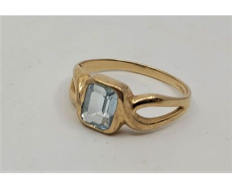 A 9ct. gold and aquamarine ring, set emerald cut aquamarine with cross-over style shoulders (gross weight 3.2g). Size: UK T.