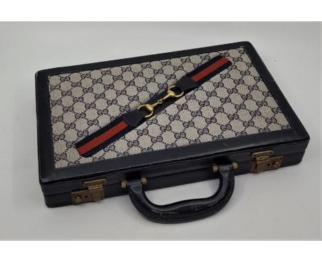 A Gucci leather cased travelling backgammon set, with twin flip lock clasps (complete with keys), opening to reveal lift-out 