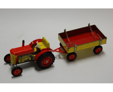 A modern tin plated clockwork model of a tractor with matching trailer