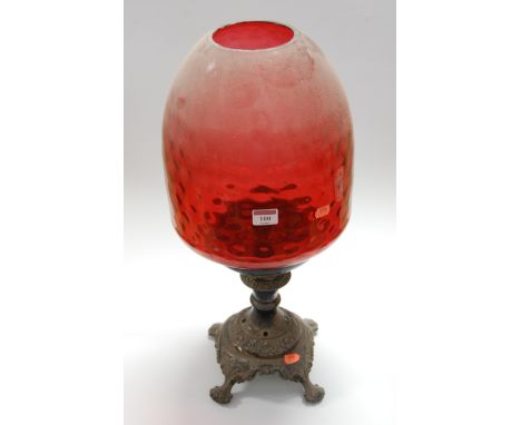 A Victorian and later adapted lamp, having a large bell shaped dimpled cranberry glass shade, on an associated silver plated 