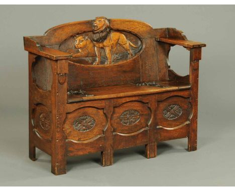 A late 19th/early 20th century hall bench, carved to the back with lions, with box seat, panelled front and raised on stile f