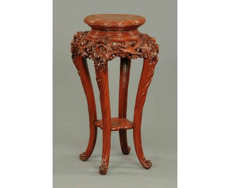 A late 19th century Oriental red lacquer carved stand, with circular top and with bird and foliate carved frieze, the legs un