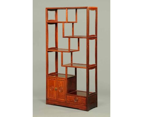 A Chinese hardwood shelf and cupboard unit, second half 20th century, fitted with a series of open shelves, cupboards and dra