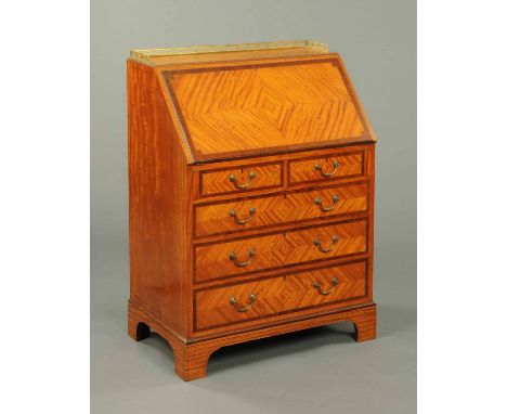 An Edwardian satinwood bureau, with three quarter brass gallery, slope front, fitted interior, leather writing surface and tw