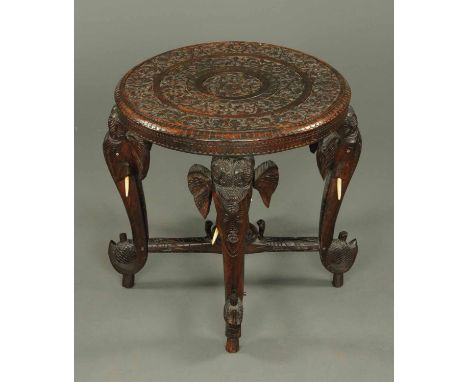 An Indian carved wooden occasional table, circular, with elephant and trunk leg supports.  Diameter 24 ins. 