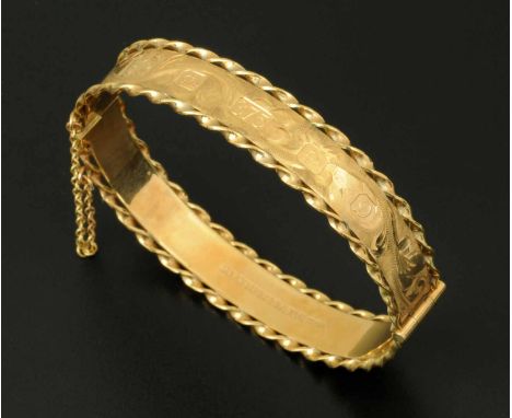 A 9 ct gold foliate engraved bangle, with safety chain, 20.6 grams (see illustration).  CONDITION REPORT: The bangle is in ex