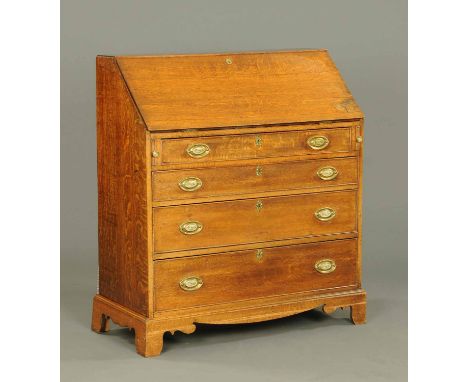 A George III oak bureau, with fall front, fitted interior and with four frieze drawers with brass drop handles and oval backp