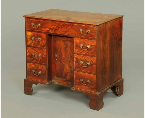 A George III mahogany kneehole desk, with moulded edge, frieze drawer, recessed cupboard, three further short drawers to eith