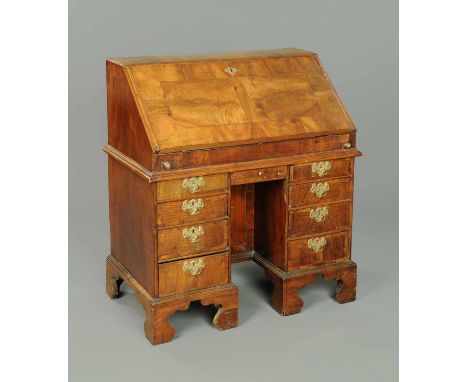 An early 19th century walnut bureau, with slope front to fitted interior, stepped and with well, with shallow central drawers