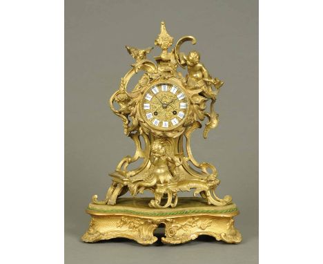 A gilt brass mantle clock, in the Louis XV style, with two-train movement and raised on carved wooden base.  Overall height 1