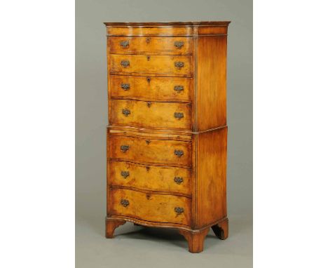 A walnut tallboy, circa 1930, in two sections, serpentine fronted and fitted with a series of graduated drawers with brass dr