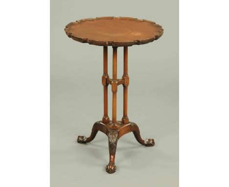 A mahogany wine table, with Chippendale border, raised on three turned columns with foliate carved downswept legs terminating