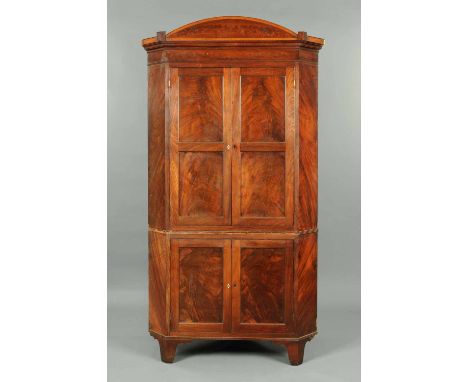 A Regency mahogany standing corner cupboard, with crossbanded and cockbeaded arched moulded cornice above a pair of panelled 