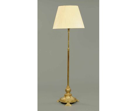 A Victorian brass lamp standard, with foliate embossed circular base raised on three spreading bracket type feet.  