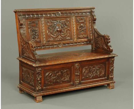 A late Victorian carved oak hall bench, the panelled back carved with a lion mask and fruit, with lift up box seat, panelled 