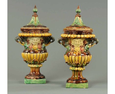 A large pair of 19th century Portuguese lidded urns, each with lobed and floral encrusted bodies and raised on a square base.