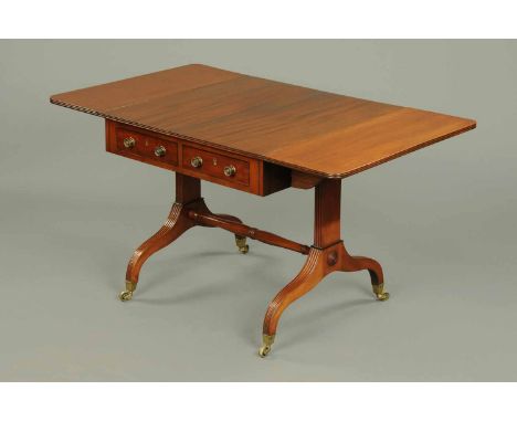 An Edwardian mahogany sofa table, in the Regency style, fitted to either side with one actual and one dummy drawer with brass