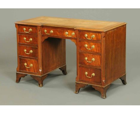 A mahogany kneehole desk, with tooled leather writing surface and series of drawers, with inverted breakfront and raised on b