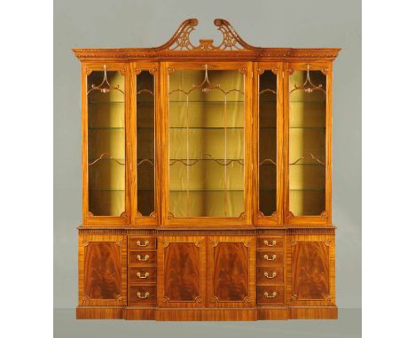 A George III style mahogany breakfront bookcase, hand carved, with swans neck pediment, egg and dart and dentil frieze above 