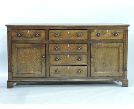 A George III oak dresser base, with six drawers, framed with cupboards, no rack, raised on bracket feet, 178cm wide, 59cm dee