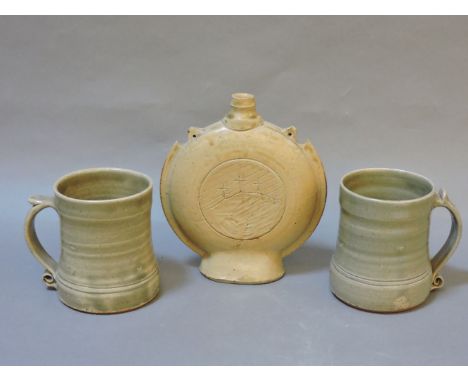 Leach pottery and Lowerdown pottery, a moon flask inscribed with the crucifixion hill, 18cm high, and two mugs, 11cm high