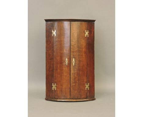 An 18th century oak bow fronted corner cupboard