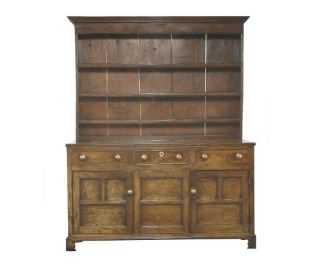 A George III oak dresser, with three shelves, with a boarded back, over three drawers and three cupboards below, raised on br