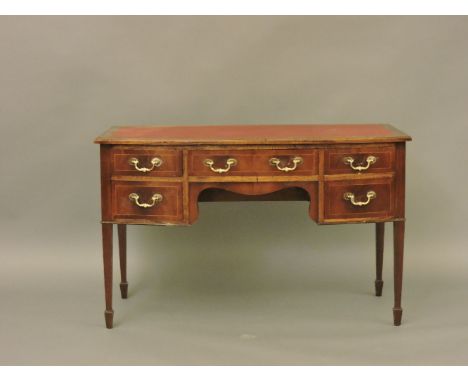 A 19th century mahogany bow front writing desk, with later red leatherette surface above a series of drawers, on square taper