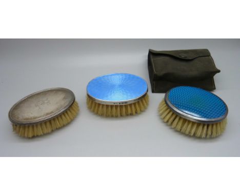 An Art Deco silver and enamel clothes brush and two similar 